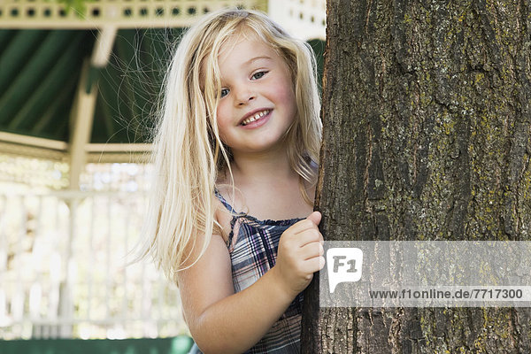 hinter  lächeln  Baum  jung  hinaussehen  Mädchen  blond