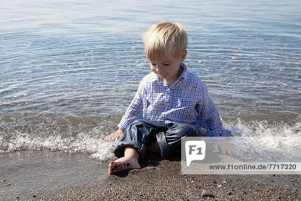 Young boy playing in the waves at the beach by lake ontario Ontario canada