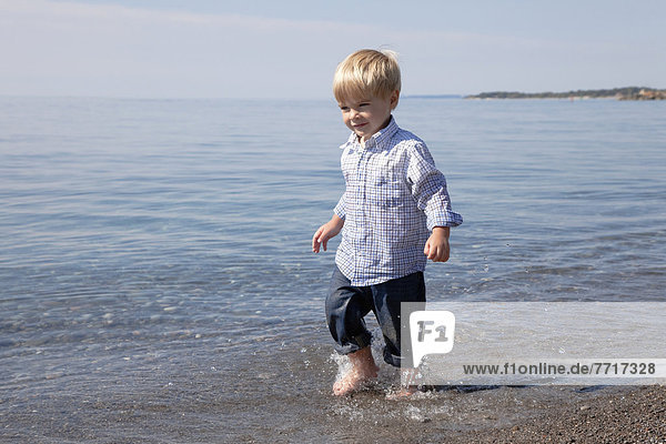 Young boy running through the waves at the beach by lake ontario Ontario canada