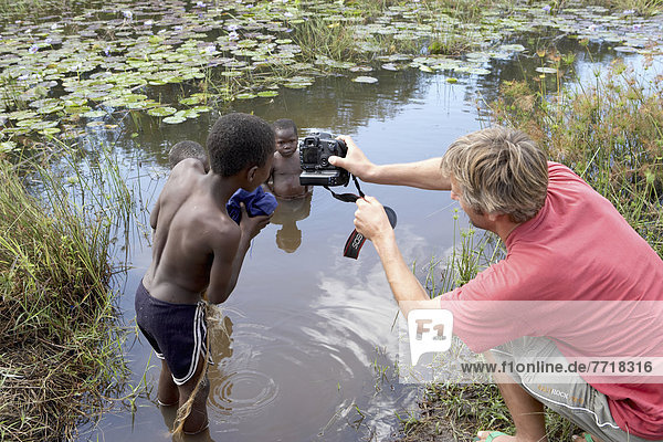 Photographer Taking Photos Of Children In River  Tanzania