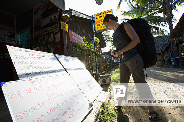 Young Female Backpacker Looking At Signs For Tours  Laos
