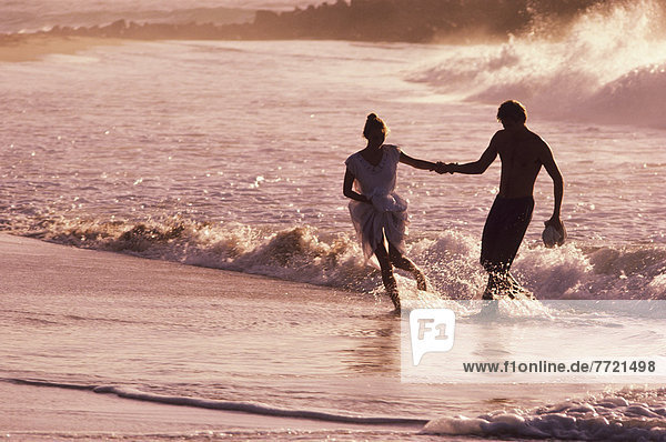 Mexico  Cabo San Lucas  Couple Playing In Ocean Waves At Sunset.