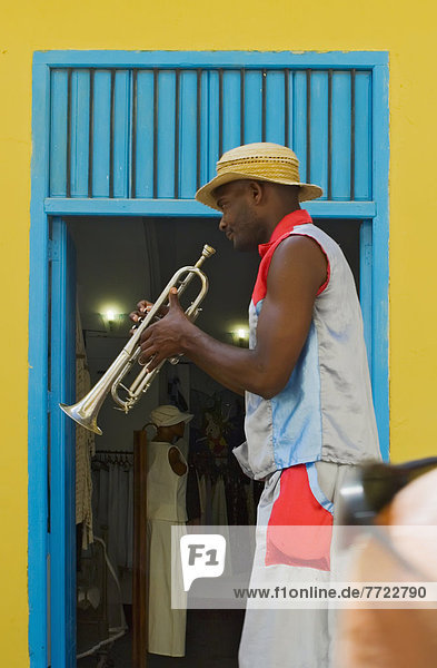 A Street Entertainer Playing A Trumpet Beside Colorful Doorway Havana Cuba