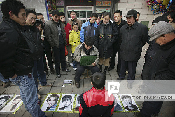 A Crowd Watching A Man Draw A Portrait Of A Boy On The Street  Xian  Xi'an  Capital Of Shaanxi Province  China