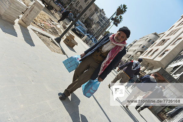 Portrait Of Senior Man Carrying Plastic Bags Of Shopping On Street  Amman  Jordan  Middle East