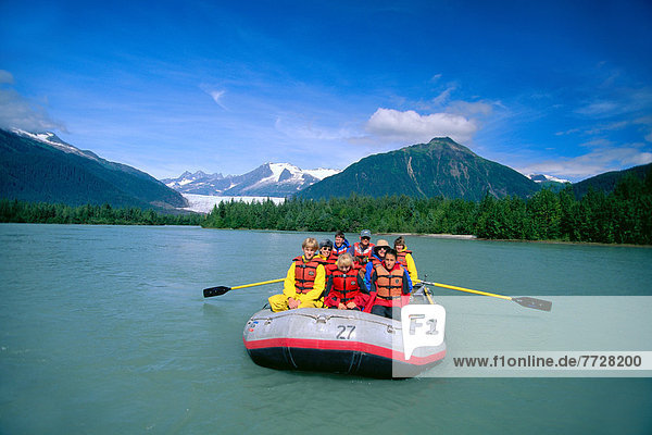 Alaska  Front View Of Group Of People In Boat Rafting  Flat Water  Blue Sky  Mountains In Background
