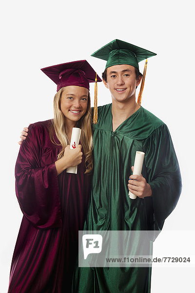Male And Female Graduates In Cap And Gown  Holding Diplomas.