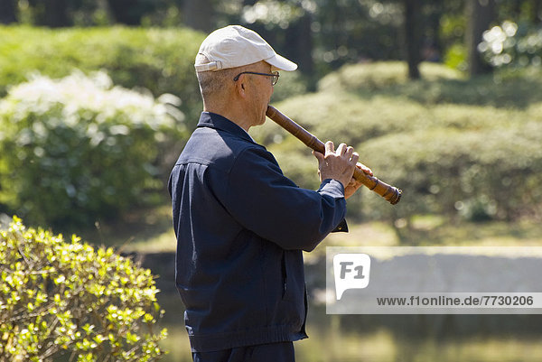 Japanese Man Playing Traditional Flute In A Park  Tokyo  Japan