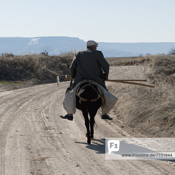 A Man Rides His Horse Down A Dirt Road Carrying Gardening Tools  Ortahisar Nevsehir Turkey