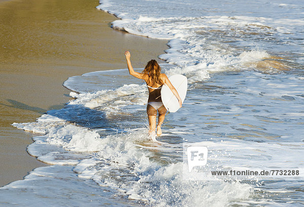 Woman running along beach with surfboard  Tarifa  Cadiz Province  Andalusia  Spain