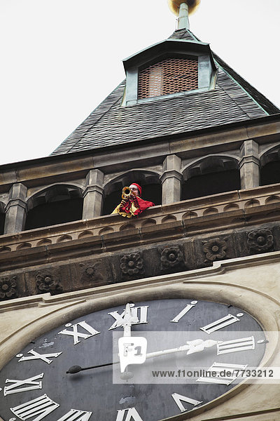 Czech Republic  Trumpeter on balcony of building with large clock  Prague