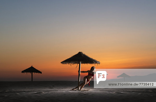 A Woman In A Bikini On The Beach Under An Umbrella At Sunset  Tarifa Cadiz Andalusia Spain