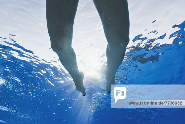 Legs swimming in a pool with sunlight shining through the water  tarifa cadiz andalusia spain