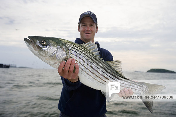 A man holding a fresh caught striped bass  boston massachusetts united states of america