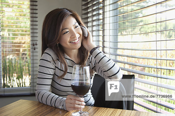A young woman talking on the phone while holding a glass of wine  berkeley california united states of america