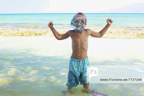 A young boy in the shallow water of the ocean with snorkelling gear Hawaii united states of america