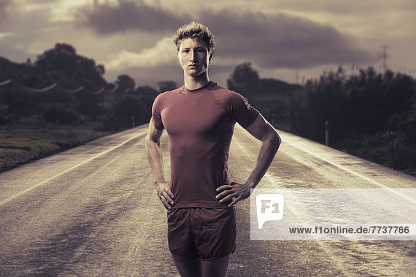 A young man poses in running shorts and t-shirt on a road Tarifa cadiz andalusia spain