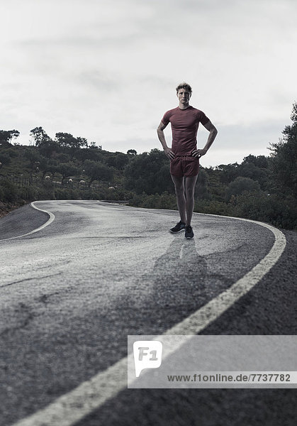 A young man in running shorts and t-shirt posing on a road Tarifa cadiz andalusia spain
