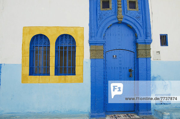 A painted blue door and bright yellow window frame on a house in old town Rabat morocco