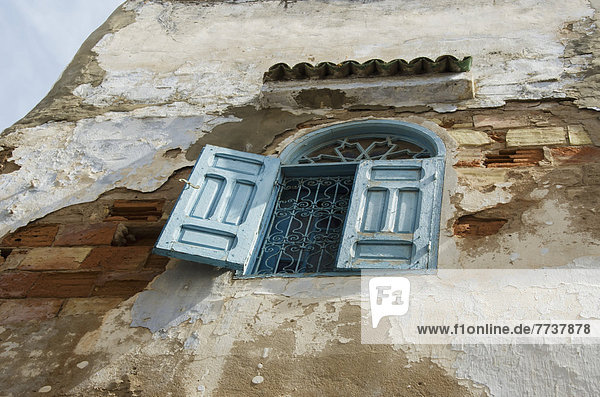 Low angle view of an open shutter on a window on a weathered and worn wall in old medina Casablanca morocco