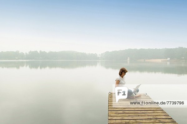 Woman with laptop on a jetty