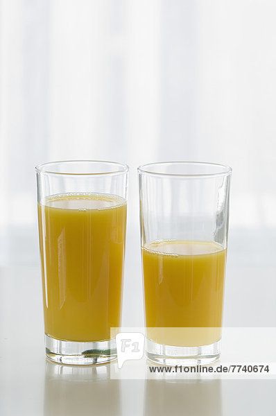 Orangensaftgläser auf Tisch vor weißem Hintergrund  Nahaufnahme