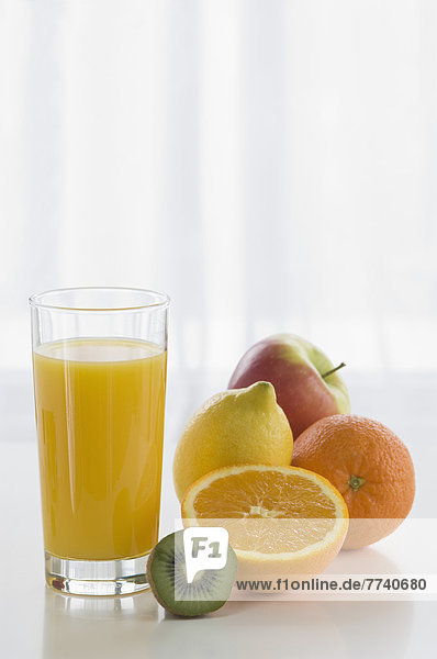Glas Orangensaft mit Früchten auf dem Tisch vor weißem Hintergrund  Nahaufnahme