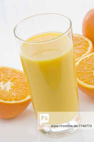 Glas Orangensaft neben Orangen auf weißem Hintergrund  Nahaufnahme