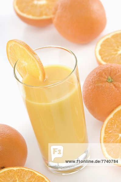 Glas Orangensaft neben Orangen auf weißem Hintergrund  Nahaufnahme