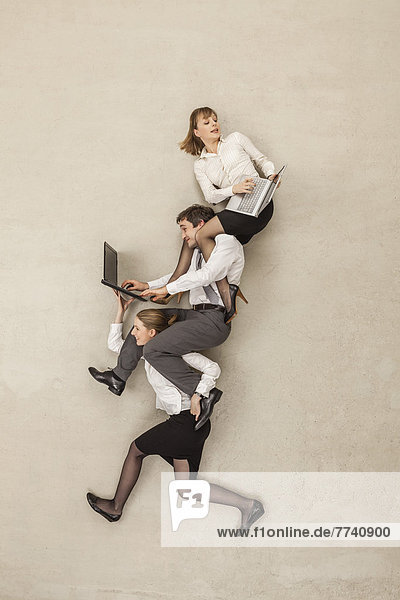 Geschäftsfrau trägt Geschäftsleute mit Laptops auf den Schultern