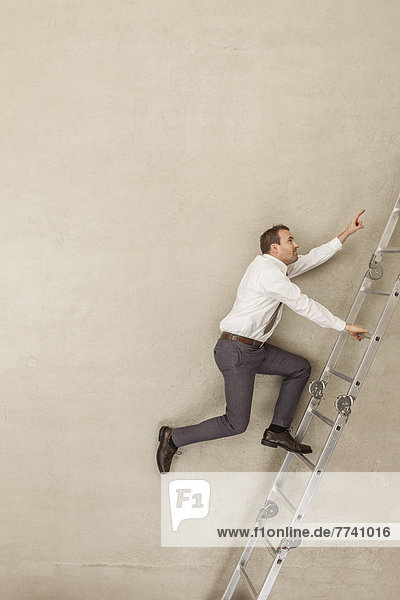 Businessman climbing ladder in office