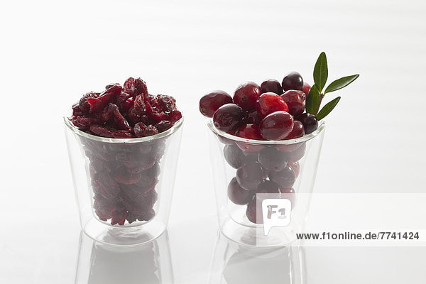 Glas frische und getrocknete Cranberries auf weißem Hintergrund  Nahaufnahme