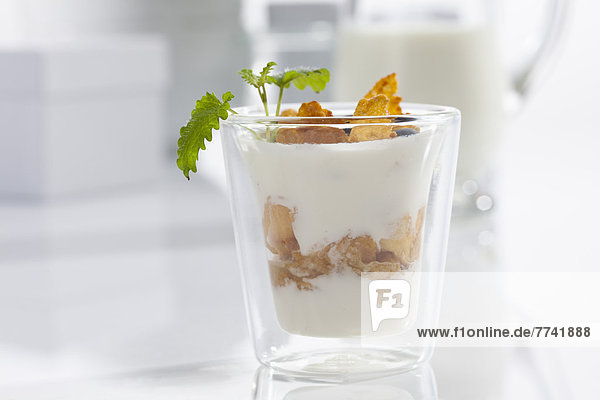 Glas Joghurt mit Müsli und Cornflakes auf weißem Hintergrund  Nahaufnahme