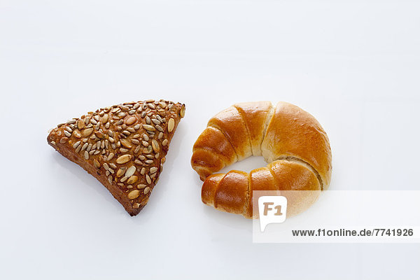 Croissant und Getreidebrot auf weißem Grund Nahaufnahme