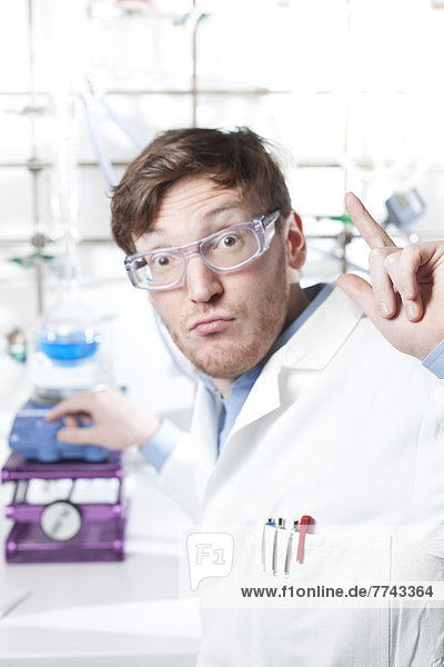 Germany  Portrait of young scientist explaining chemical process  smiling