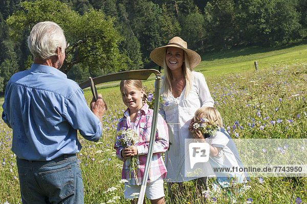 Deutschland  Salzburg  Bauer und Familie auf der Sommerwiese  lächelnd