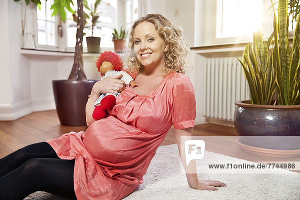 Porträt einer schwangeren Frau mit Puppe  lächelnd