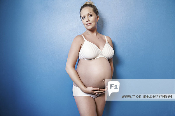 Schwangere Frau hält ihren Bauch  lächelnd  Portrait