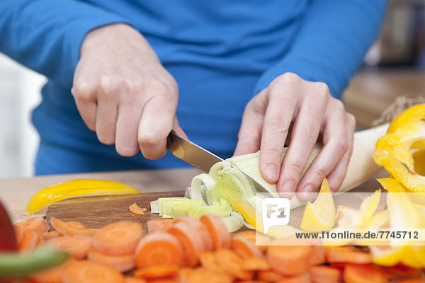 Junge Frau hackt Gemüse in der Küche  Nahaufnahme