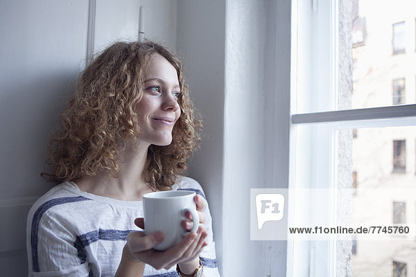 Young woman looking out of window  smiling