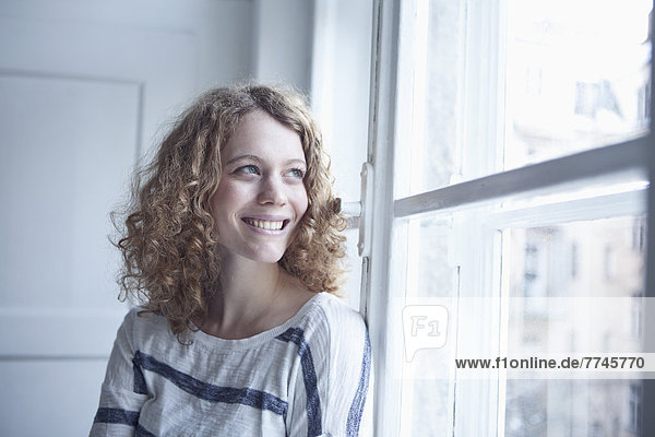 Young woman sitting at window  smiling