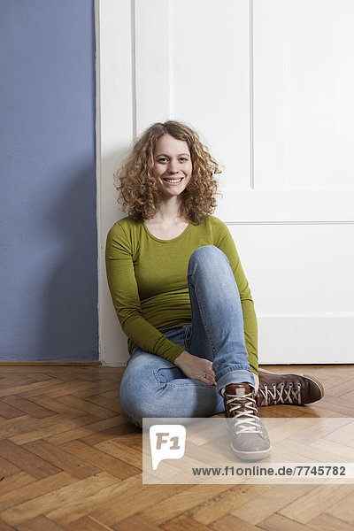 Young woman sitting on floor  smiling  portrait