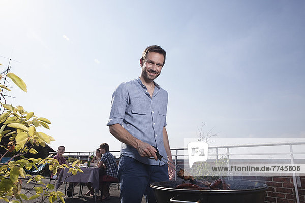 Portrait of man barbecueing on grill  smiling