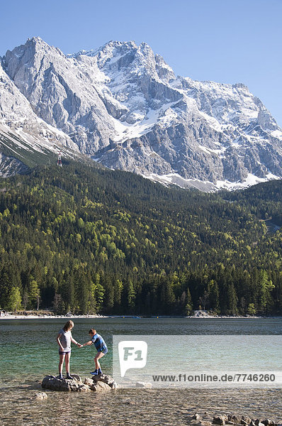 Boy and girl playing on Lake Eibsee with Zugspitze mountain in background