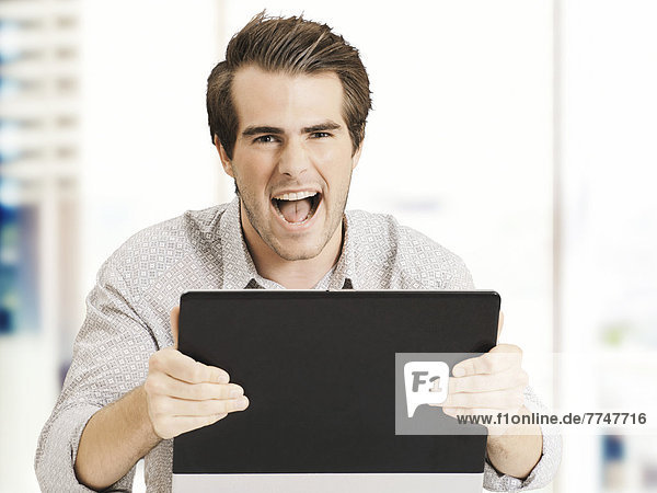 Businessman with laptop  screaming with joy