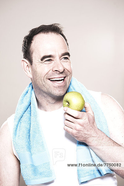 Lachender Mann mit Handtuch um den Hals hält einen Apfel  Portrait