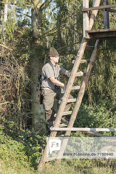 Jäger besteigt einen Hochsitz