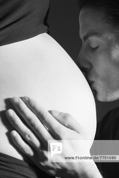 Werdender Vater küsst den Bauch seiner schwangeren Partnerin