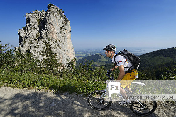 Mountain biker cycling in front of Staffelstein rock at Mt Kampenwand