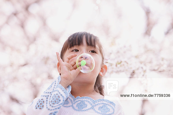 Young girl playing with soap bubbles